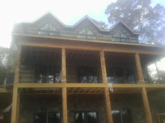 Dormers and porch framing on a large log home under construction — Roof Coating work by our crew in Lowman