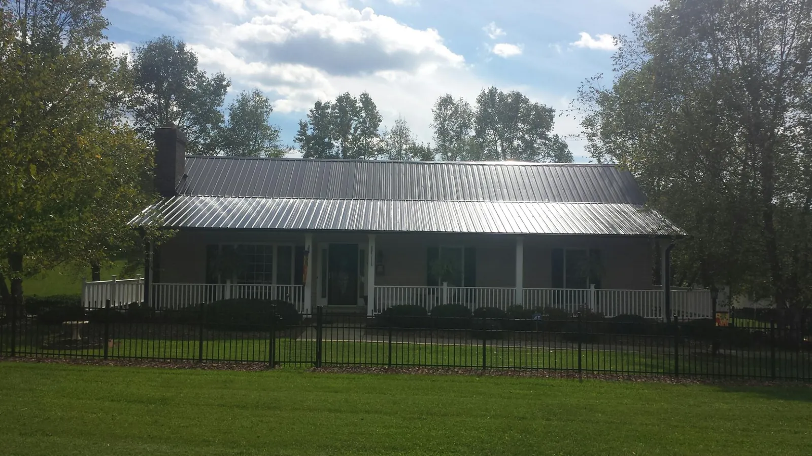 Gray metal roof on a brick ranch with a full width front porch — Gutter Guard Installation work by our crew in Lowman