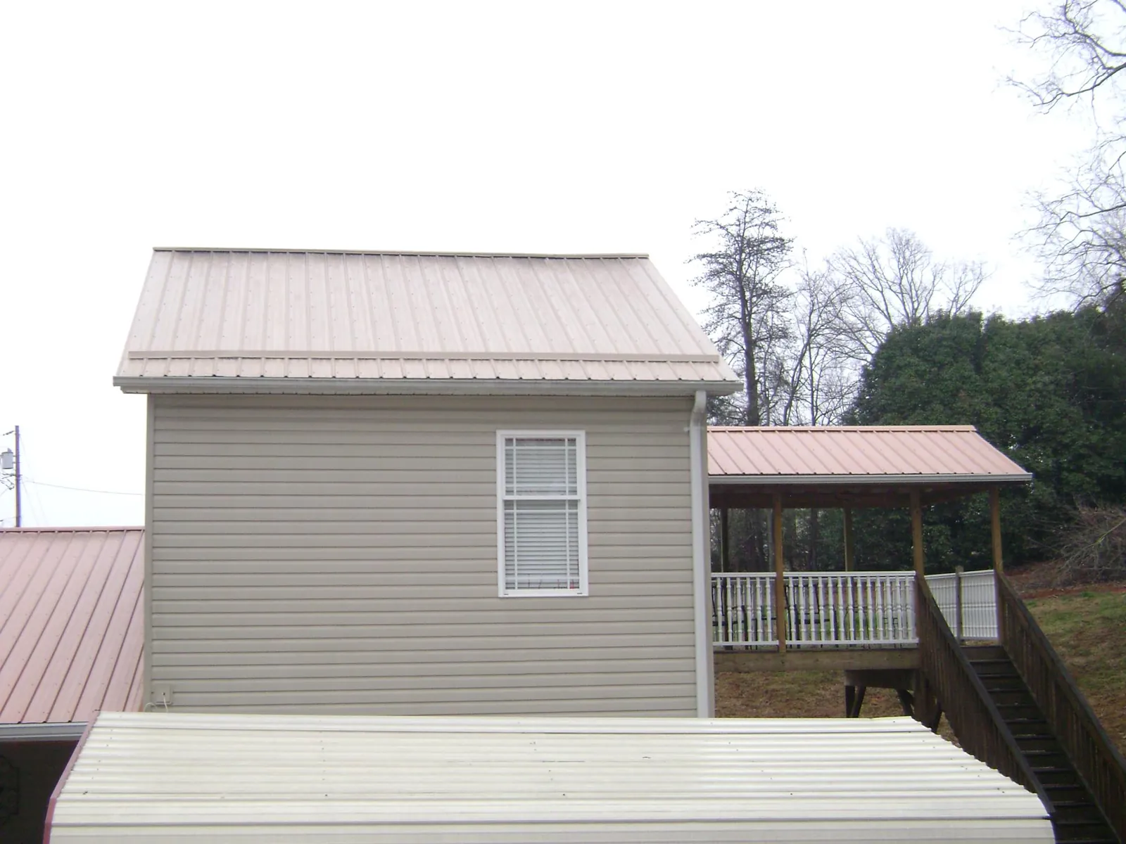 Tan metal roofs on a two story addition and attached porch in Lowman