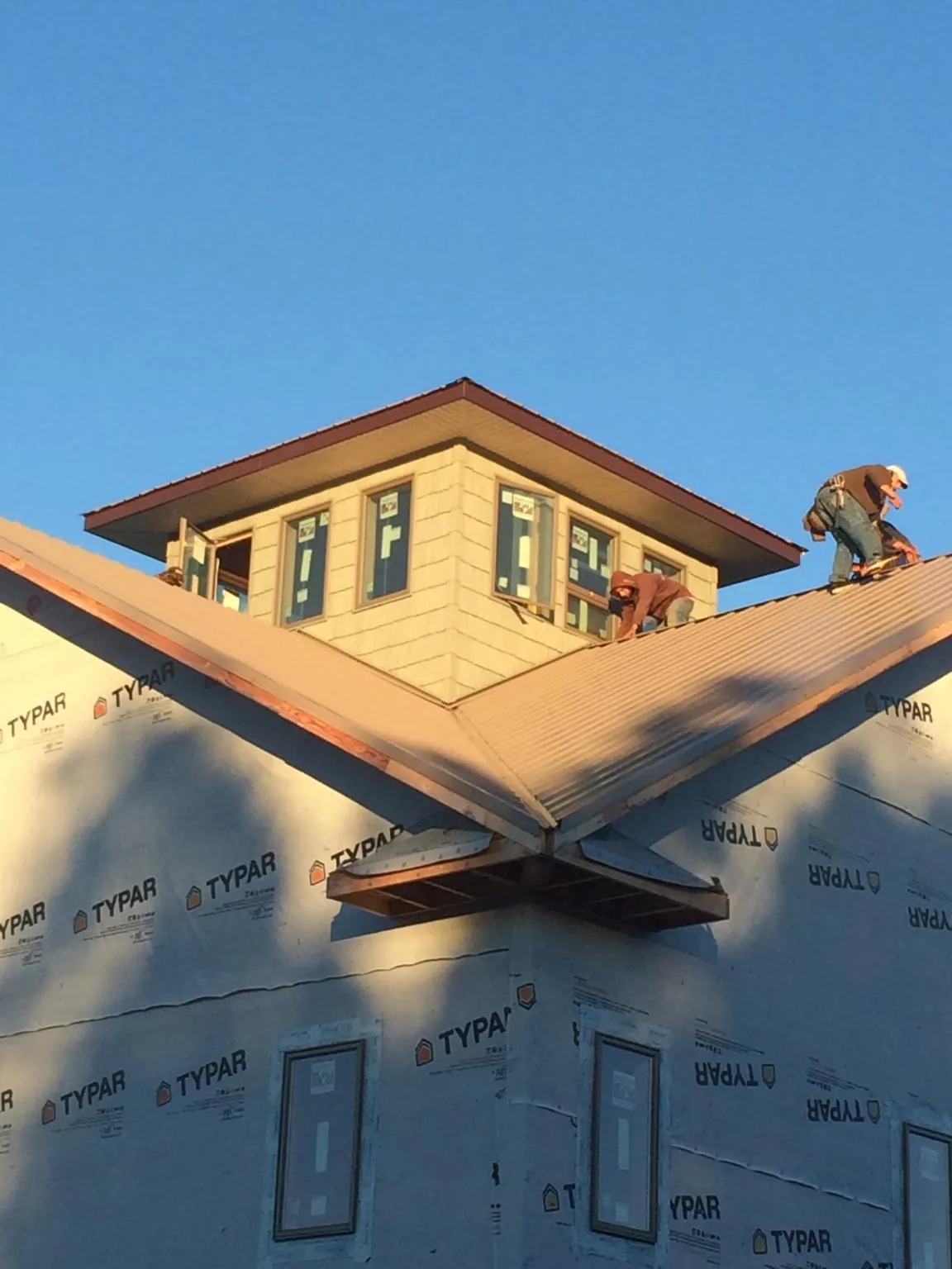 Roofers working around a rooftop cupola on a new metal roof at sunset — Roof Waterproofing in Lowman by Roofing Brothers